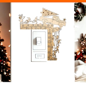 Puede incluir: Una cubierta de interruptor de luz de Navidad de madera con un camión que lleva un árbol de Navidad y duendes colgando de las luces. La cubierta está diseñada para adaptarse a un interruptor de luz estándar.