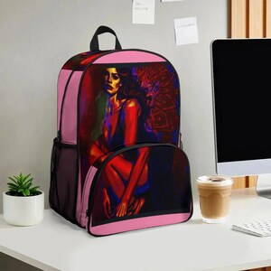 以下が含まれることがあります： 赤と青の色調で女性を描いた鮮やかな絵画が特徴のピンク色のバックパック。 バックパックには黒いハンドル、サイドメッシュポケット、黒いトリムが付いています。 アートワークは、ピンクの背景に対して焦点となっています。
