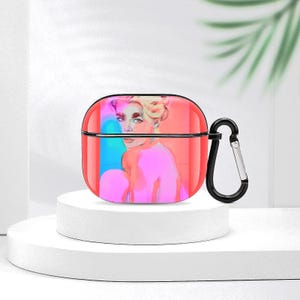 May include: Red and black AirPod case featuring a colorful illustration of a person. The case has a black carabiner clip attached. The artwork has pink, blue, and yellow tones.