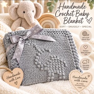 May include: A gray crochet baby blanket featuring a textured elephant pattern, tied with a gray ribbon printed with small white hearts. The blanket includes two heart-shaped wooden tags labeled Handmade with Love and Handmade with Love By Three Generations.
