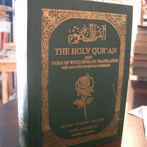 May include: A dark green hardcover book, "THE HOLY QUR'AN", with English translation. The cover features gold lettering and a rose illustration. Includes Arabic and Turkish translations. Published by Rayna Publication, Turkey-Ankara.