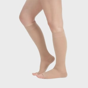 May include: Beige compression socks, knee-high style, with open toes. The socks are made of a smooth, opaque material and are designed to provide support. The socks are shown on a person's legs.