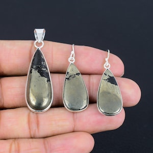 May include: A set of silver earrings and a pendant featuring teardrop-shaped pyrite stones. The stones have a dark gray and gold color.