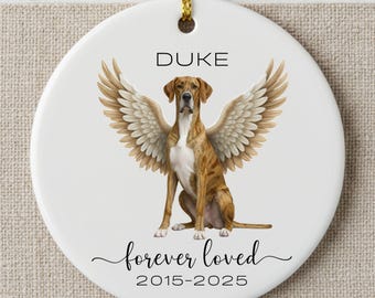 May include: A white ceramic ornament with a dog illustration and angel wings. The dog is brown and white with the name "DUKE" above it. The text "forever loved" and the years "2015-2025" are below the dog.