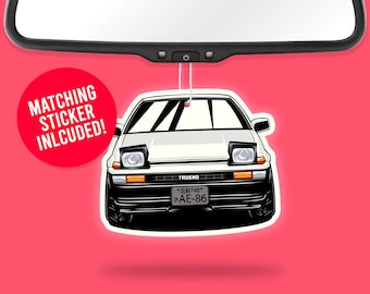 May include: White car air freshener with a black bumper and black headlights. The car has a license plate that reads "*818748* AE-86". The air freshener is hanging from a rearview mirror. The text "MATCHING STICKER INLCUDED!" is in a red circle.