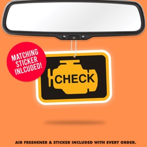 Może przedstawiać: Żółto-czarny odświeżacz powietrza do samochodu z napisem "CHECK" w stylizowanym symbolu silnika. Odświeżacz powietrza wisi na lusterku wstecznym. Czerwone koło z napisem "MATCHING STICKER INCLUDED!" znajduje się w lewym górnym rogu obrazu.