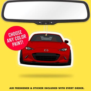 Puede incluir: Un ambientador para coche con forma de coche rojo, colgado de un espejo retrovisor. El ambientador es una ilustración estilizada de un coche deportivo rojo. Un círculo rojo con el texto "CHOOSE ANY COLOR PAINT!" está a la izquierda.