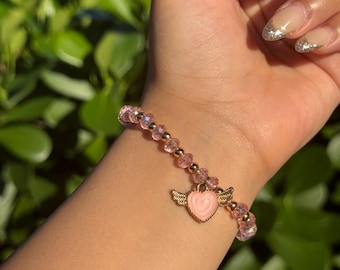 Pulsera de cuentas de cristal rosa claro con dije de corazón de alas de ángel y detalles dorados