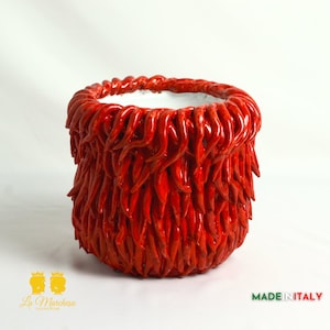 May include: Red ceramic planter shaped like a chili pepper. The planter is made in Italy and has a white interior.