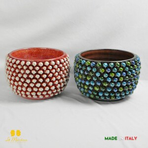 Op de afbeelding: Twee decoratieve keramische kommen. Eén is rood met witte accenten, de andere is blauw en groen. De kommen hebben een textuur, kralenontwerp. De tekst "MADE IN ITALY" is zichtbaar.
