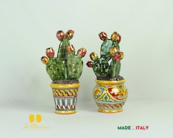 Op de afbeelding: Twee keramische cactusplanten in kleurrijke potten. De cactusplanten zijn groen met rode en gele bloemen. De potten zijn versierd met gele, rode, blauwe en groene ontwerpen. De tekst "MADE IN ITALY" is zichtbaar in de rechterbenedenhoek van de afbeelding.