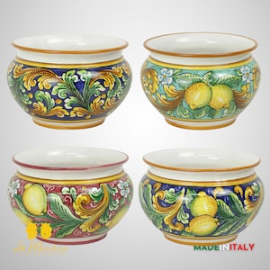 May include: Four ceramic planters with a white background and colorful floral and lemon designs. The planters have a rounded shape and a wide rim. The designs include green leaves, yellow lemons, and blue, red, and green floral patterns.