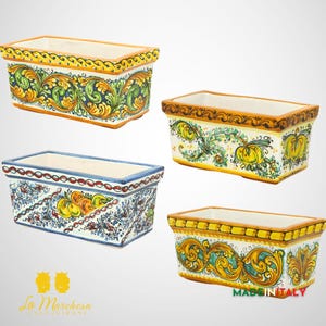 Può includere: Quattro vasi rettangolari in ceramica con diversi disegni floreali. I vasi sono bianchi con accenti gialli, verdi, blu e arancioni. I vasi sono tutti della stessa dimensione e forma. Il testo "MADE IN ITALY" è visibile nell'angolo in basso a destra dell'immagine.