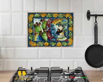 Op de afbeelding: Een kleurrijke keramische tegel met een blauwe achtergrond, een gele lijst en een schilderij van een man met een baard en een kroon. Het schilderij toont ook een cactusplant met groene bladeren en rode bloemen.