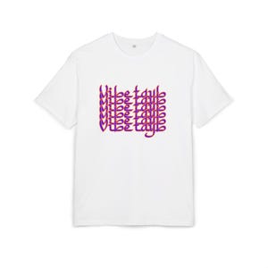 Könnte beinhalten: Weißes T-Shirt mit einem sich wiederholenden Muster der Wörter "Vibe Tayb" in Lila und Rot. Das T-Shirt hat einen klassischen Rundhalsausschnitt und ist aus weichem Material gefertigt.