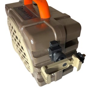 May include: A tan and brown rectangular box with an orange handle. The box has a speaker-like grill on one side and a mounting bracket on the side. The handle has the word "SOX" printed on it.