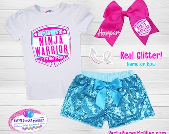 May include: A white t-shirt with a pink and blue graphic that says "Harper's Ninja Warrior 7th Birthday". A pair of turquoise sequined shorts with a light blue bow. A pink bow with the text "Harper" and a small pink and blue graphic that says "Ninja Warrior".