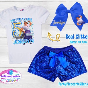 May include: A white t-shirt with a blue and gold number 5, a cartoon character, and the text "Birthday Girl" and "Jordyn". Blue sequined shorts with a blue bow. A blue bow with the name "Jordyn" and a cartoon character. The text "Real Glitter! Name on bow" is also included.