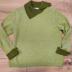 Könnte beinhalten: Ein hellgrüner Pullover mit dunkelgrünem Kragen und Bündchen. Der Pullover hat eine gerippte Struktur und eine lockere Passform.