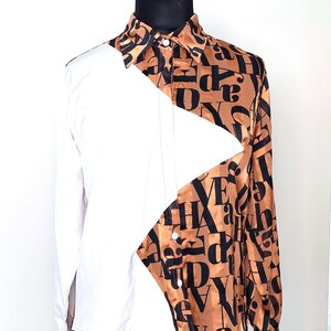 May include: A white and brown button-up shirt with a diagonal pattern of black letters on the brown side. The shirt has a long sleeve and a collar.
