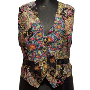 Puede incluir: Un chaleco vintage con un diseño de patchwork con estampados florales en tonos rosa, amarillo, turquesa y negro. El chaleco tiene cuello en V, botones dorados y ribete de satén negro. Una prenda única y colorida.