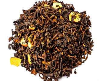 May include: A close-up of a pile of loose leaf black tea with pieces of dried fruit, likely apple, scattered throughout.