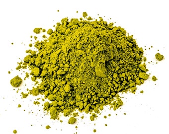 May include: A pile of bright green matcha powder on a white background.