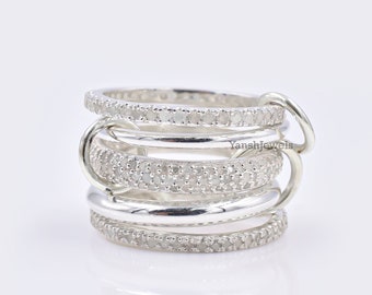 May include: Silver ring with multiple bands, each set with small clear stones. The ring has a dangling charm with the text "Yanshjewels".