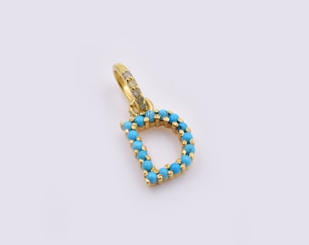 May include: Gold charm in the shape of the letter D, with turquoise stones around the edges.