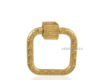 May include: A gold-colored square clasp with a geometric design. The clasp has a square center with a maze-like pattern and a rectangular frame with a repeating pattern. The text "ASSHI JEWELS" is visible on the right side.