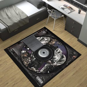 Puede incluir: Una alfombra negra y plateada con un gran diseño circular que se asemeja a un disquete. El diseño presenta un disquete plateado con una etiqueta negra y un fondo negro y plateado. La alfombra tiene un borde negro y el texto "Parental Advisory Explicit Content" está impreso en blanco en la parte inferior.