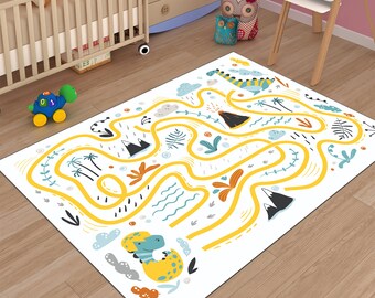Puede incluir: Una alfombra de juego blanca con un laberinto amarillo e ilustraciones coloridas de dinosaurios. El laberinto presenta un volcán, palmeras y nubes.