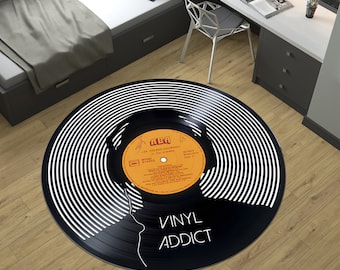 Könnte beinhalten: Schwarz-weißer Vinyl-Platten-Teppich mit einer Silhouette einer Person mit Kopfhörern. Das Plattenlabel lautet "ABA LES FRERES  JACQUES" und "GRAND STEREO". Der Text "VINYL ADDICT" ist auf dem Teppich gedruckt.
