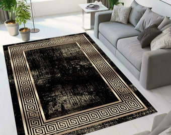 May include: Black and gold area rug with a distressed, vintage look. The rug features a large, intricate Greek key border.