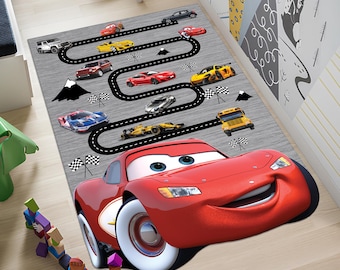 May include: A red cartoon race car with a smiling face is the centerpiece of this gray rug. The rug features a black race track with various colorful cars and a school bus.