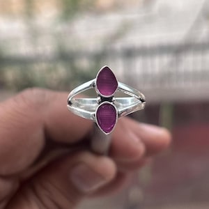 May include: A silver ring with two teardrop-shaped purple stones.