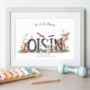 May include: A framed print featuring the name OISÍN in large dark letters surrounded by watercolour illustrations of a fox, squirrel, hedgehog, raccoon, rabbit, and deer. Text reads Ar Lá Do Bhaiste, March 21st 2026, and St. Marys Church, Maynooth.