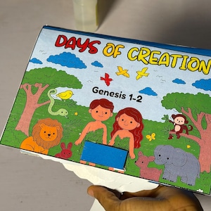Könnte beinhalten: Kinderbuchcover mit dem Titel "DAYS OF CREATION" und dem Text "Genesis 1-2". Die Illustration zeigt Adam und Eva sowie verschiedene Tiere wie einen Löwen, einen Affen und einen Elefanten, in einer farbenfrohen Umgebung.