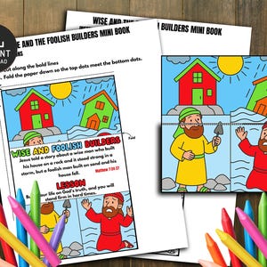 Puede incluir: Un minilibro infantil colorido titulado "Wise and Foolish Builders" con ilustraciones de casas y figuras. El texto incluye instrucciones y una lección sobre la construcción sobre una roca. Lápices de colores están dispuestos alrededor del libro.