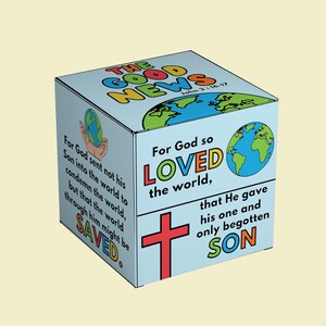 May include: A blue cube with the words "The Good News" in colorful letters. The cube has a red cross and a world map on it. The text "For God so loved the world, that He gave his one and only begotten Son" is written on the cube.