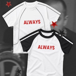 May include: Two short-sleeved t-shirts with the word ALWAYS printed in red. The top shirt is white with black piping. The bottom shirt is a white raglan style with black sleeves and a black collar. Both shirts feature red star graphics.