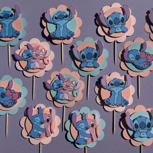 Puede incluir: Doce adornos para cupcakes azules y rosas con Stitch y Angel de la pel&iacute;cula de Disney Lilo & Stitch. Los adornos est&aacute;n hechos de cartulina y presentan varias poses de los personajes.