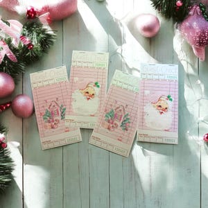 May include: Four pink Christmas-themed guest check receipts with illustrations of Santa Claus and a house. The receipts have the text "Guest Check" and the number "122521". The background includes pink ornaments and greenery.