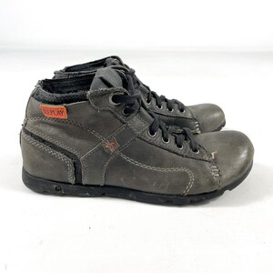 May include: A pair of gray leather ankle boots with black laces and soles. The boots have a distressed look, with visible stitching and the brand name "REPLAY" on a small orange tag.
