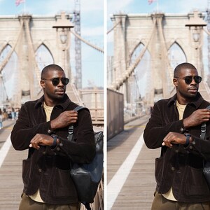 May include: A person wearing a brown corduroy jacket, a beige t-shirt, and dark green pants. They are wearing sunglasses and a watch. They are standing on a bridge with a backpack slung over their shoulder. The bridge is made of stone and has a metal railing. The background is a city skyline.