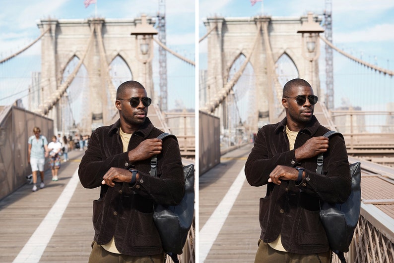 May include: A person wearing a brown corduroy jacket, a beige t-shirt, and dark green pants. They are wearing sunglasses and a watch. They are standing on a bridge with a backpack slung over their shoulder. The bridge is made of stone and has a metal railing. The background is a city skyline.