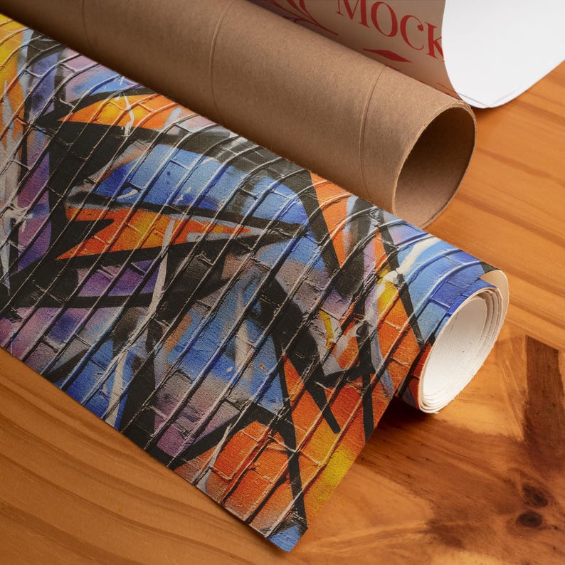 Op de afbeelding: Opgerolde kunstprint met een graffiti-ontwerp met baksteenachtige patronen in oranje, blauw, paars en zwart. Een bruine kartonnen koker is zichtbaar op een houten oppervlak.