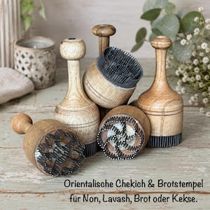 Könnte beinhalten: Eine Sammlung von Holz-Brotstempeln mit aufwendigen Designs. Die Stempel haben einen abgerundeten Griff und eine gemusterte Basis, ideal für die Erstellung dekorativer Abdrücke auf Backwaren. Der Text auf dem Bild lautet: "Orientalische Chekich & Brotstempel für Non, Lavash, Brot oder Kekse."