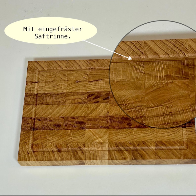 May include: A rectangular wooden cutting board with a juice groove. The board is made of light brown wood and has a textured surface. The text "Mit eingefr&auml;ster Saftrinne" is in a yellow oval.
