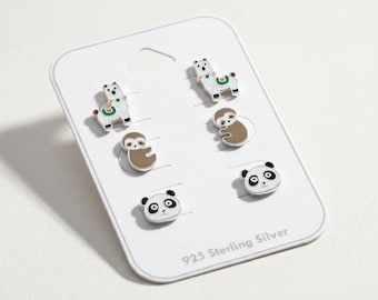 May include: A set of three pairs of 925 sterling silver stud earrings on a white display card. The designs include white llamas with green accents, brown sloths, and black and white panda faces. Each earring features enamel detailing.